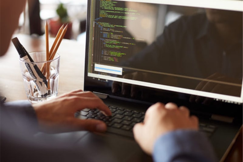 Laptop screen displaying MERN stack code and development environment for Java DevOps Full Stack training.