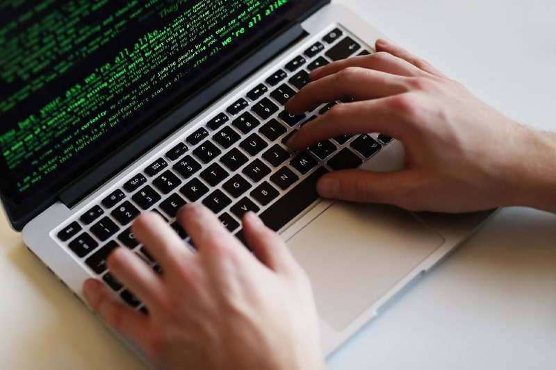 Hands typing Java code on laptop for SynergisticIT training program.