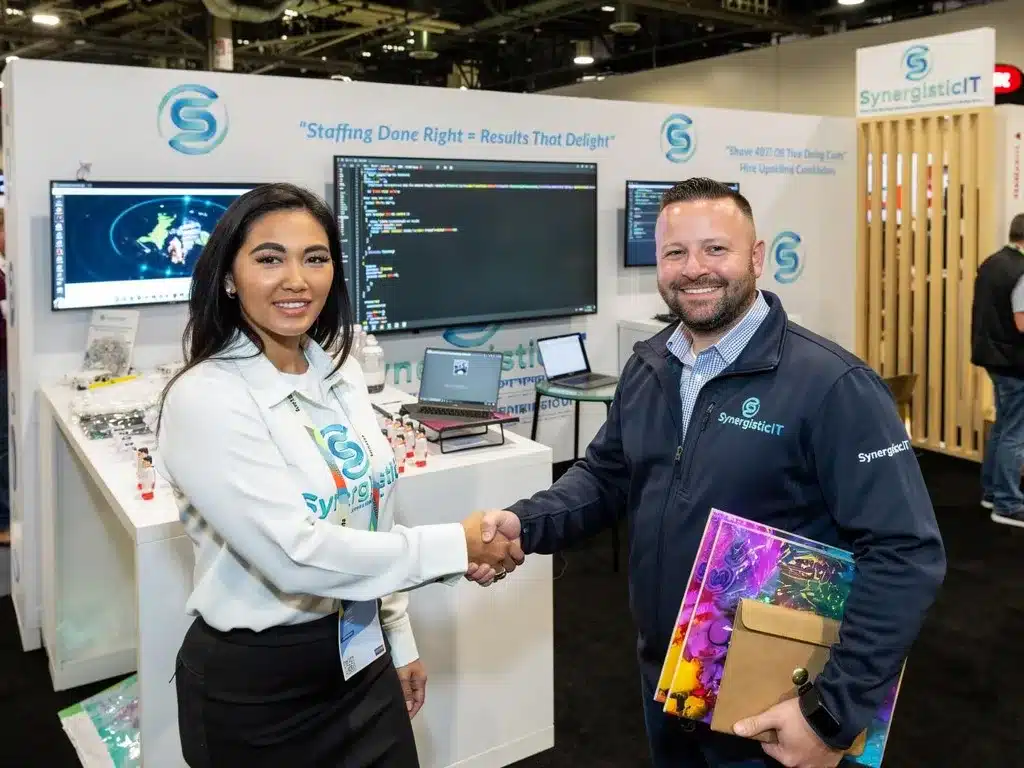 SynergisticIT staffing event with smiling professionals shaking hands, showcasing technology and career opportunities.